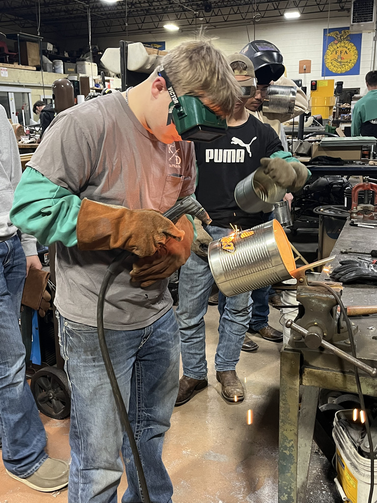 A student uses a heat treatment on his tin can jack-o-lantern.
