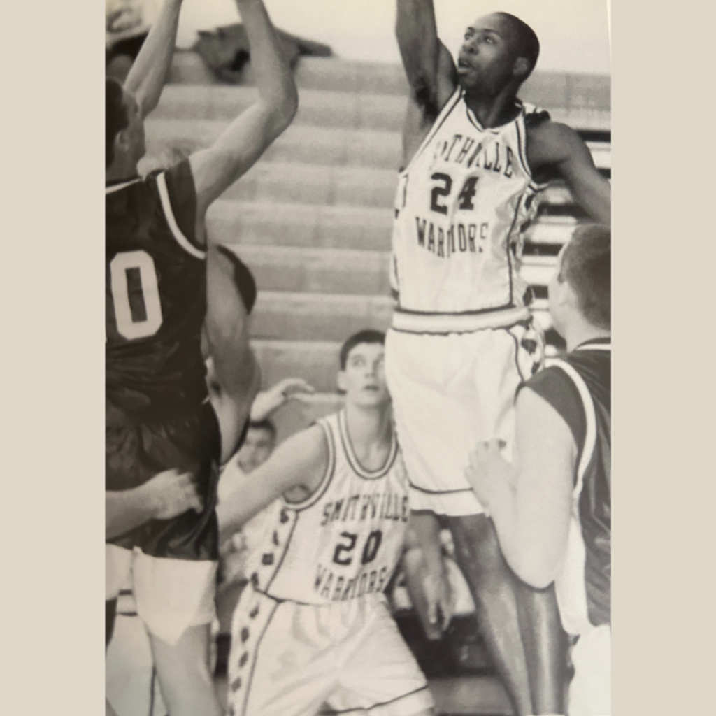 A Smithville boys basketball player goes up for a shot. Other players are blocking and preparing to rebound.