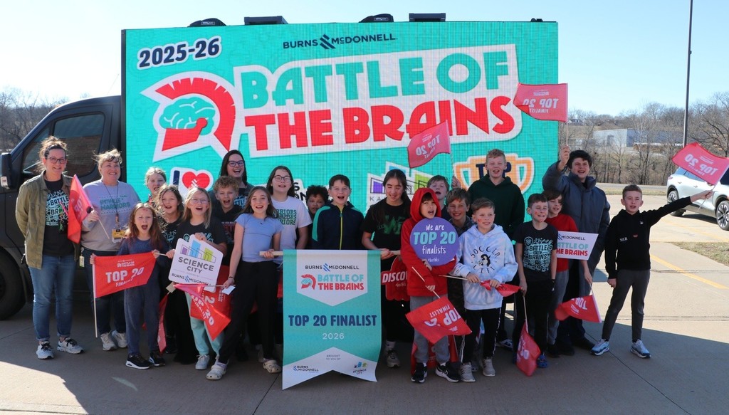 Students post for a picture in front of a box truck that has a Battle of the Brains graphic on the side.