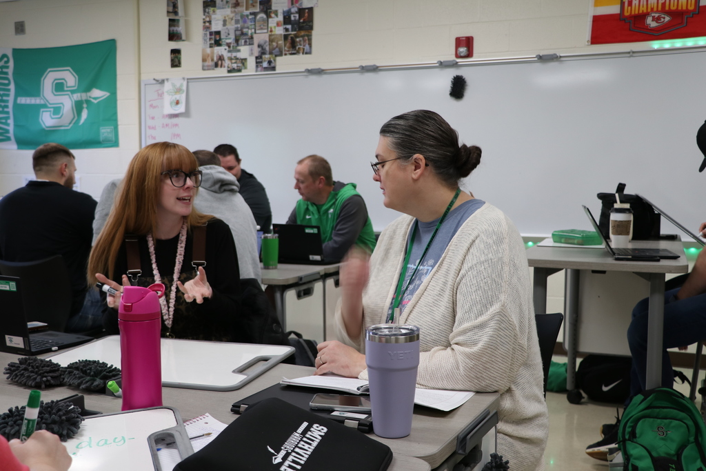 Teachers discuss and write on a white board.