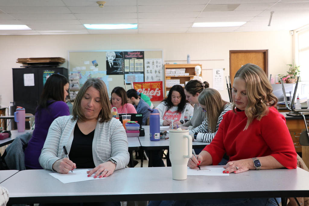 a teacher draws a heart on a piece of paper while in a professional development about art therapy.