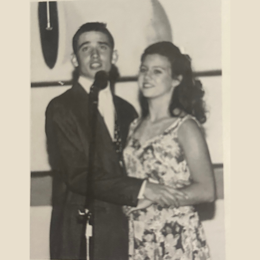 Actors in a school play sing a duet into a microphone.