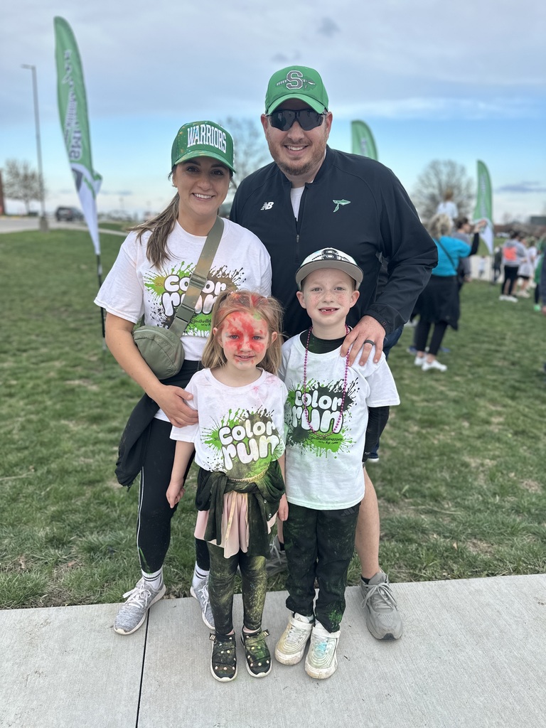 A family poses for a picture at the color run. The kids are covered in colored powder.