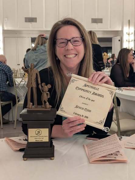 Stacia Cudd smiles big while holding her certificate for citizen of the year.