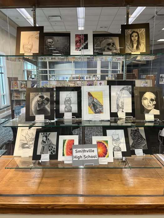 A window display of artwork with the sign Smithville High School in front of it.