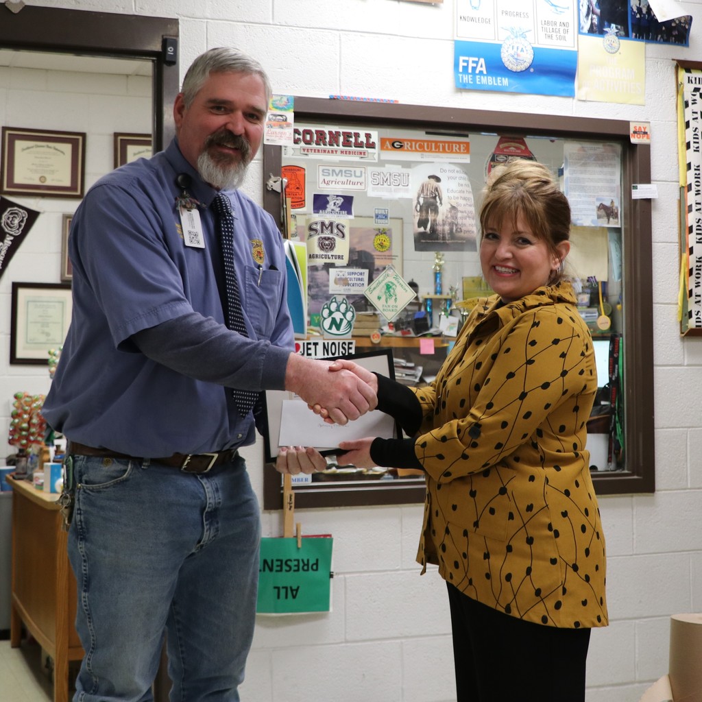 Mr. Viebrock shakes the hand of the FFA representative as she hands him an award.