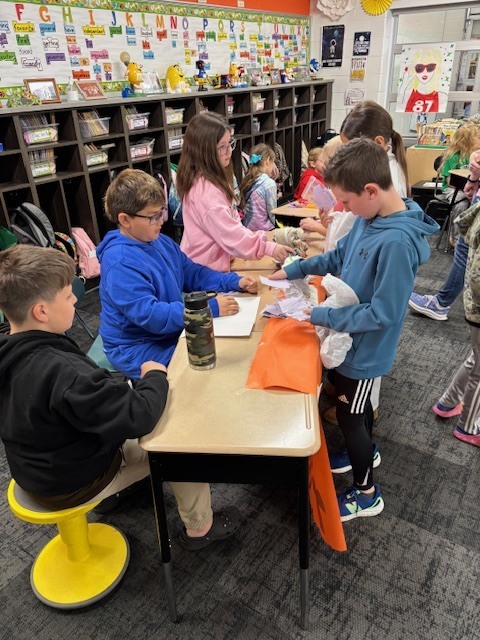 Students exchange pretend money for goods for their economics unit.