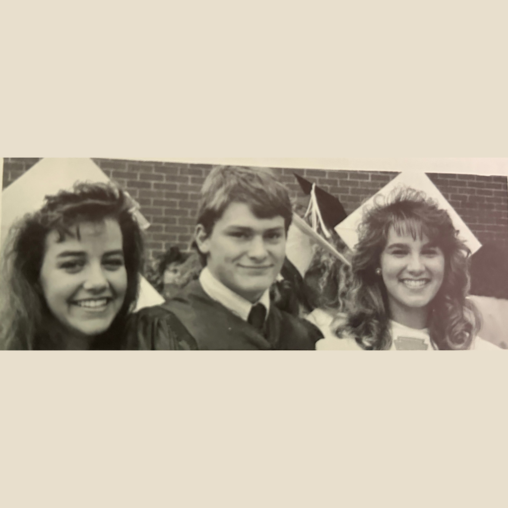Three graduates in their caps and gowns smile for a picture