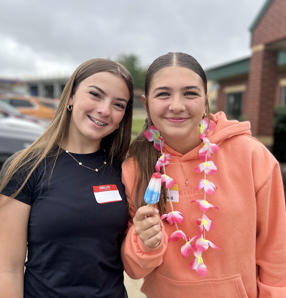 Girls pose for a picture with a bomb pop popsicle in hand.