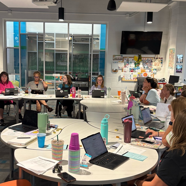 teachers sitting around a table listening to a presentation