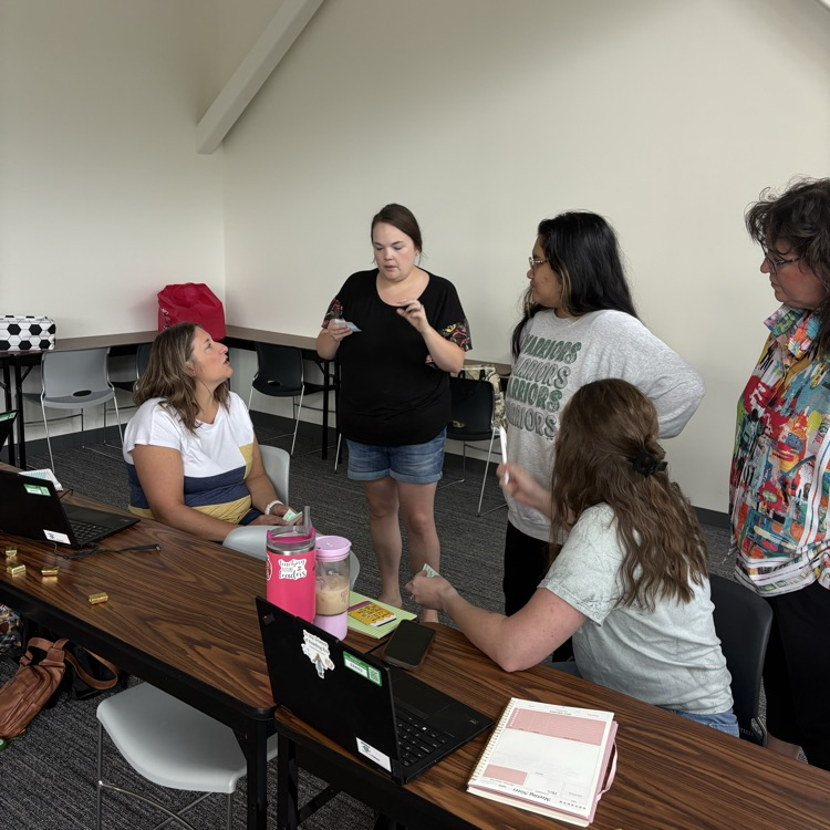 Teachers talking in small groups at a meeting