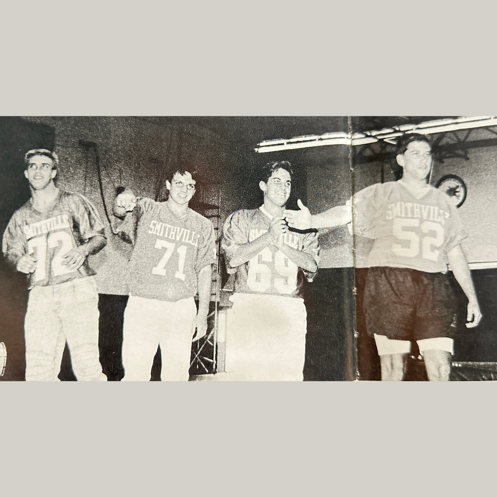 Black-and-white yearbook photo of four members of the 1989 Smithville High School football team wearing Smithville football jerseys and standing together at an event. The players are smiling and posing for the camera.