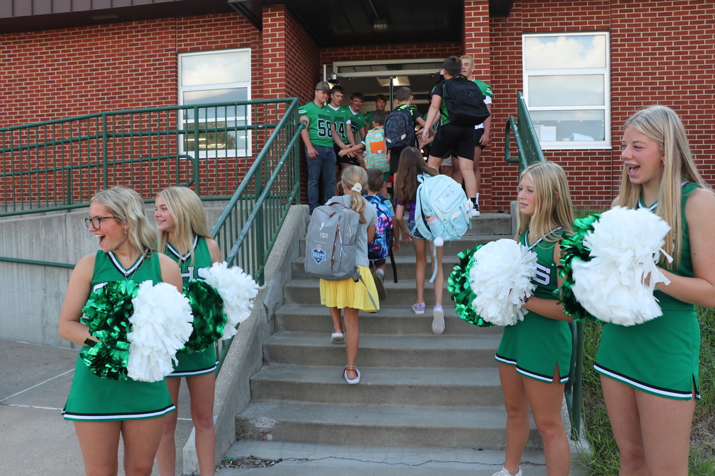 Cheerleaders and football players greet elementary students when they arrive at school.