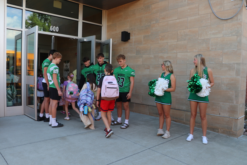 Cheerleaders and football players greet elementary students when they arrive at school.