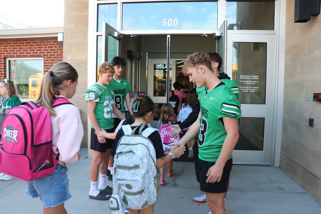 Cheerleaders and football players greet elementary students when they arrive at school.