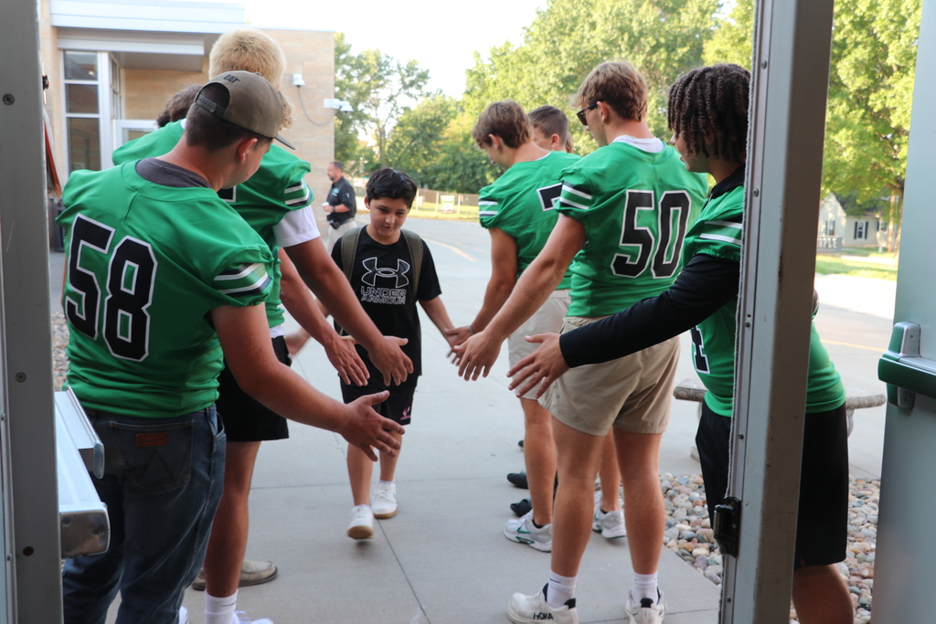 Cheerleaders and football players greet elementary students when they arrive at school.