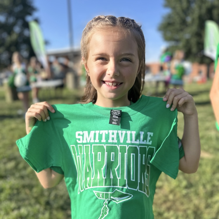 a little girl holding up her warrior tshirt