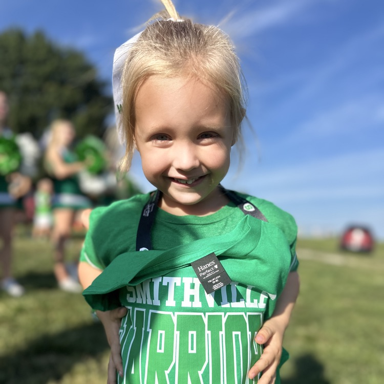 a little girl holding up her warrior tshirt