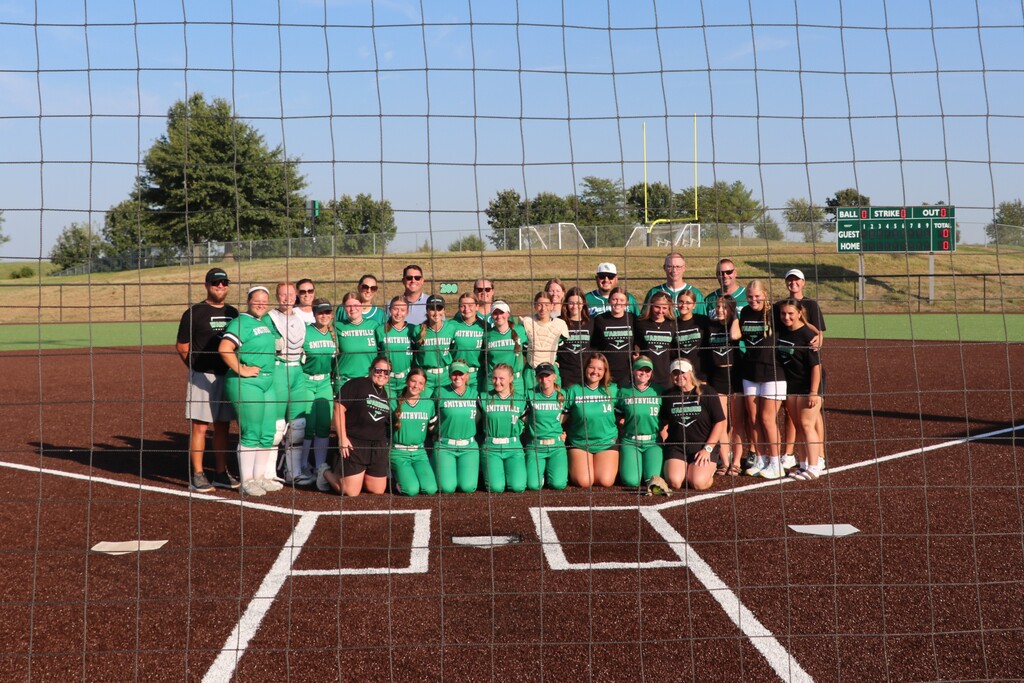 The team and the board of education pose for a picture on the field