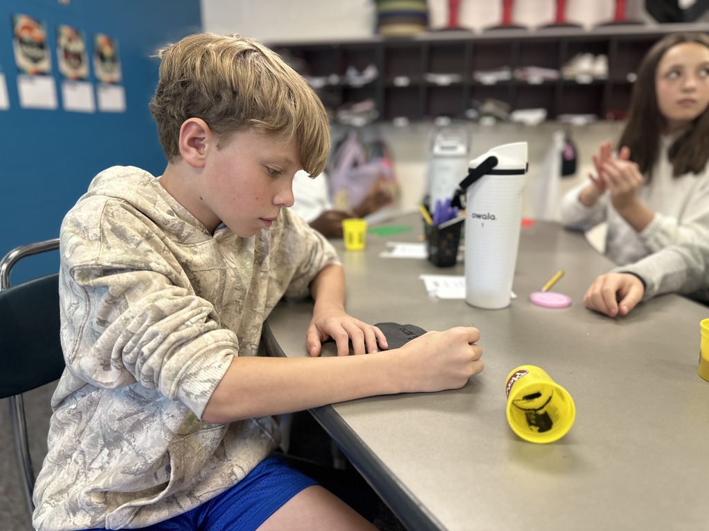 A boy carves his name into playdough using Cuneiform