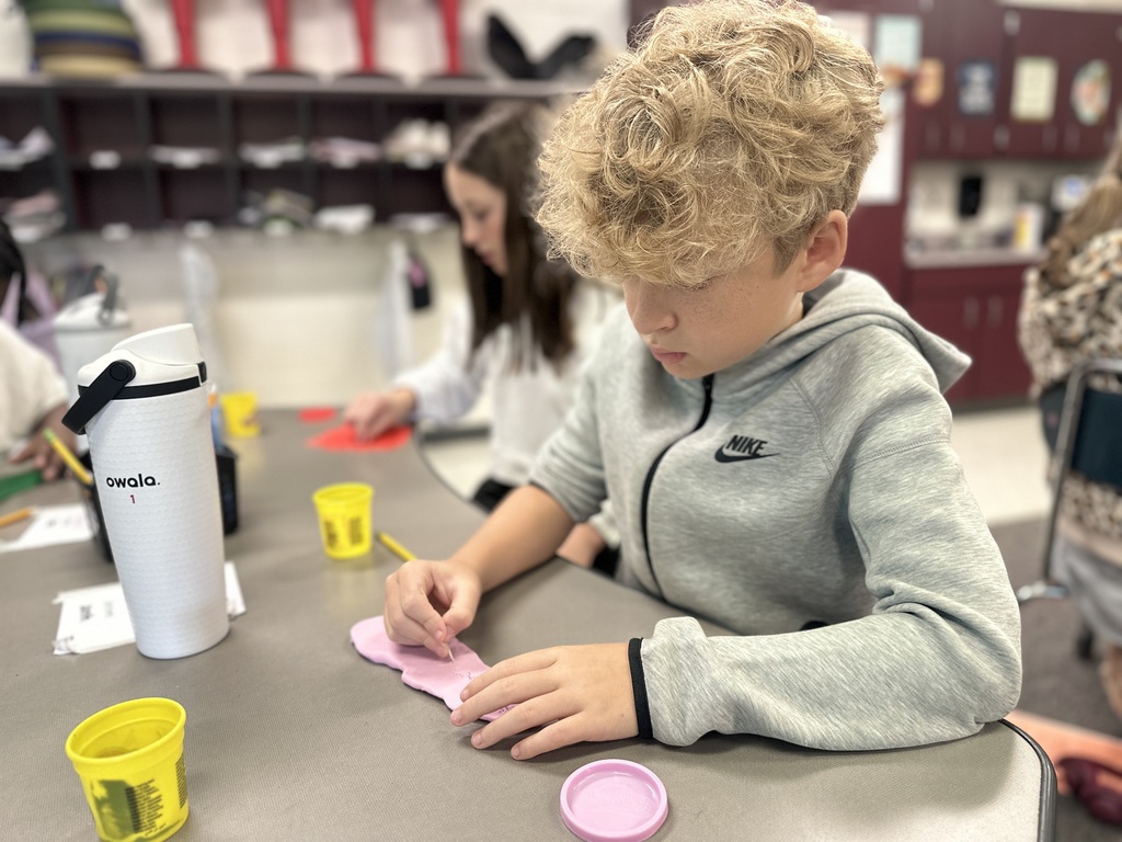 A boy carves into playdough with a toothpick