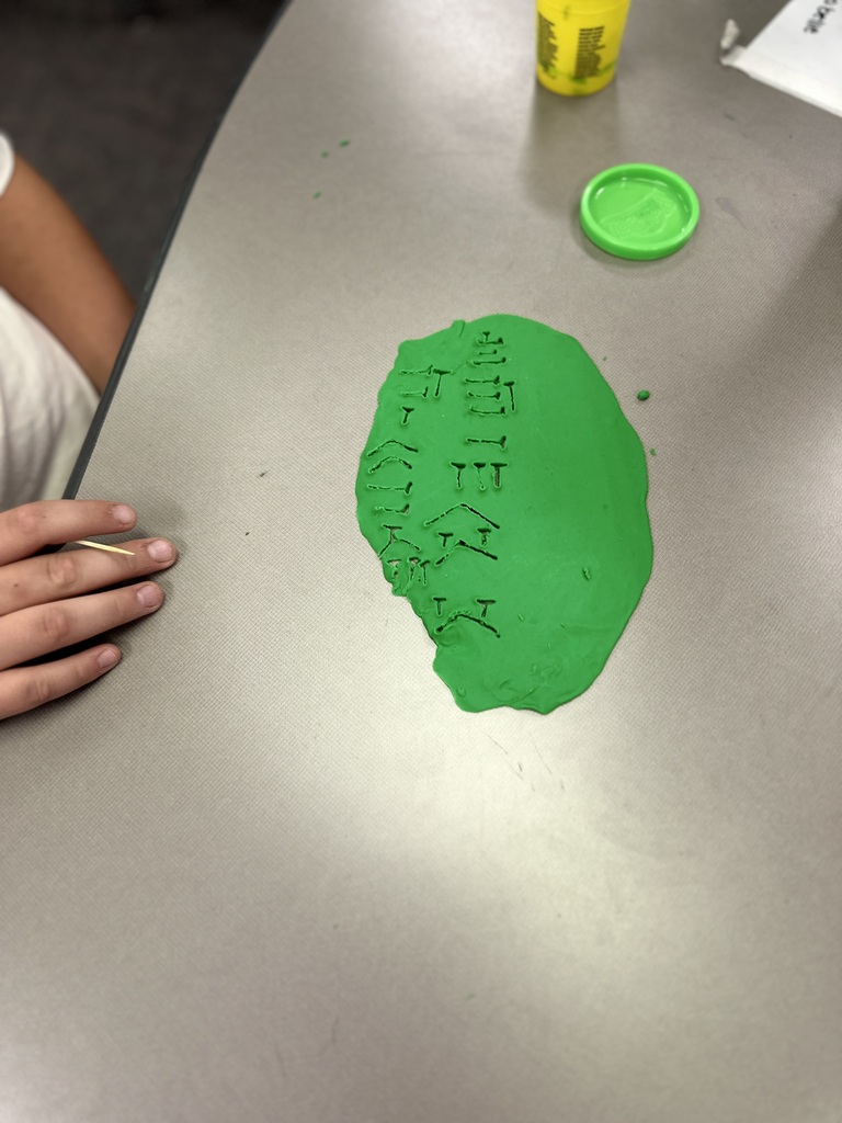 Green playdough has Cuneiform letters carved into it