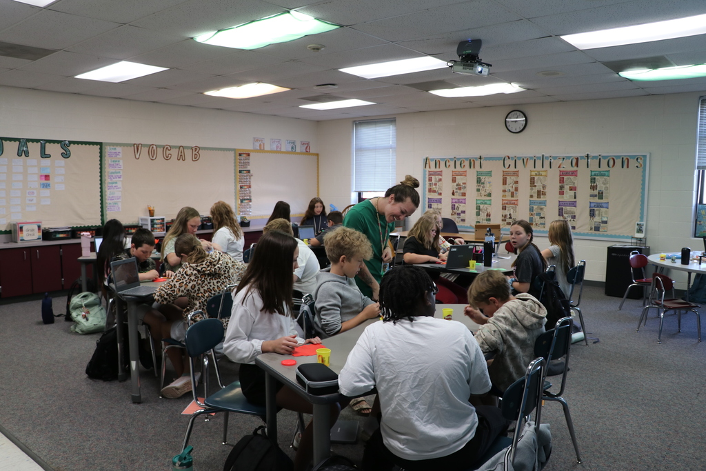 Miss Schoonover looks at what a student carved into their playdough and smiles