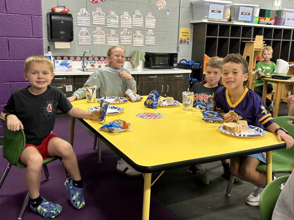 Students eat lunch at a little yellow table