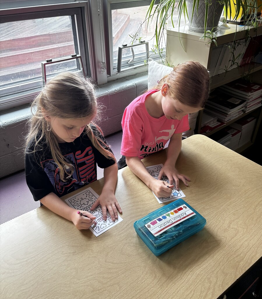 Girls sit next to each other and color