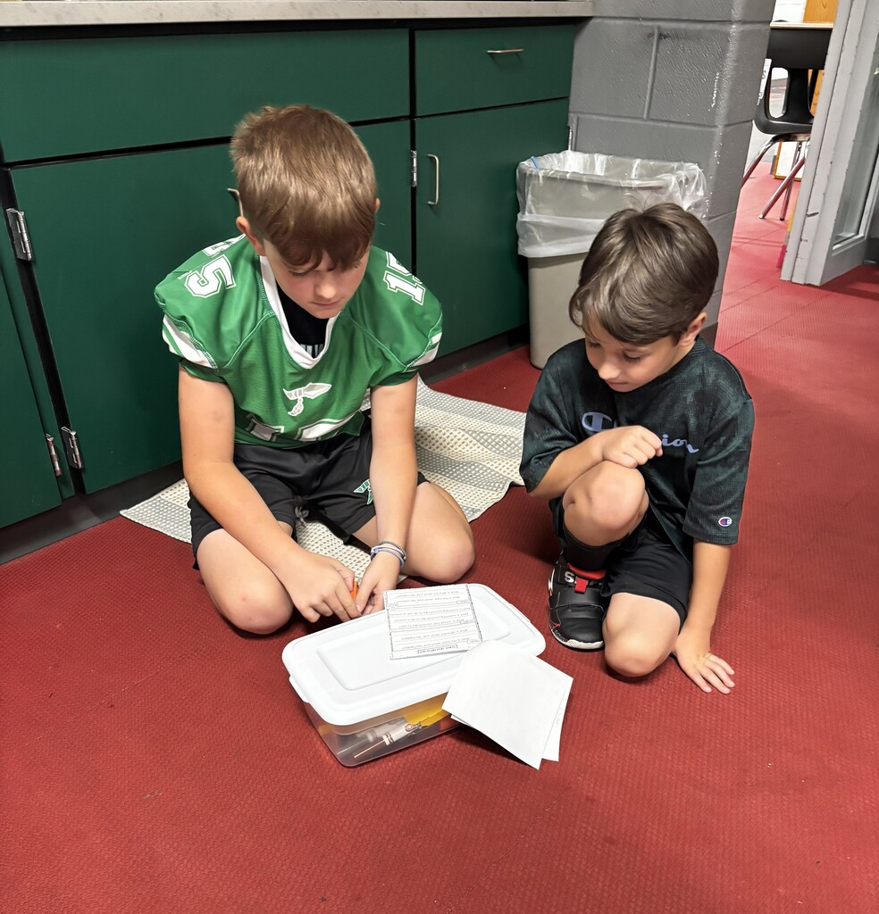 An older boy works with a younger boy on a story