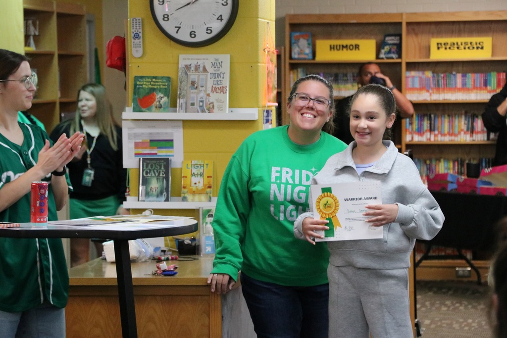 A teacher poses with her student with her award
