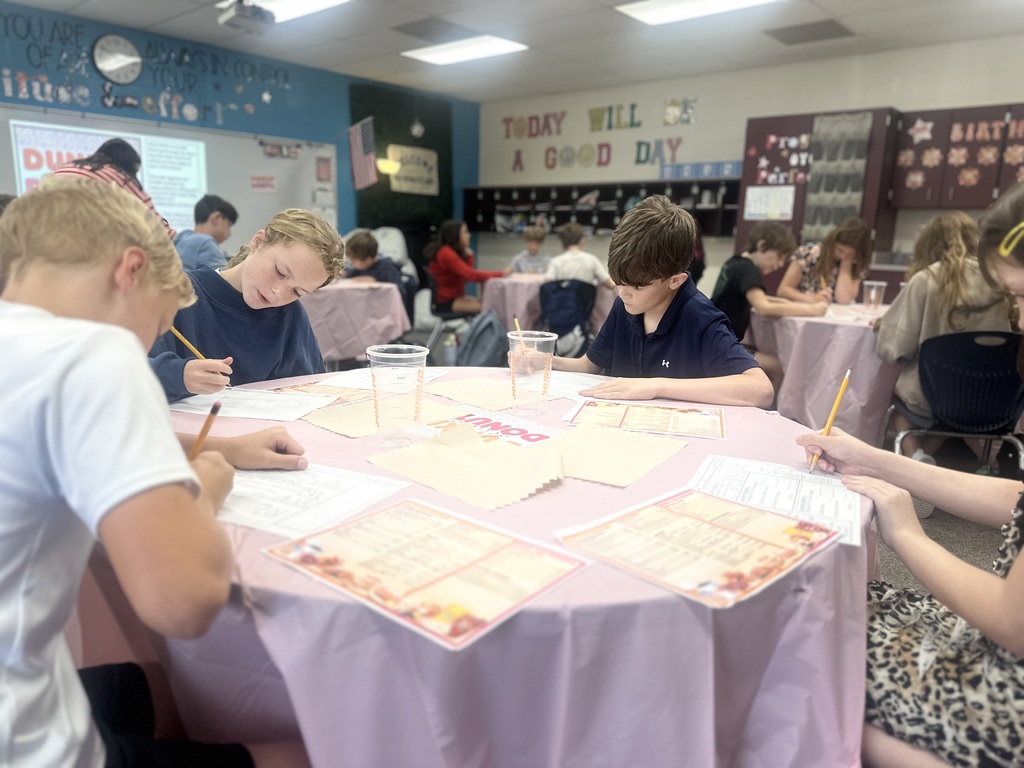 A table of students are working on their worksheets to find the customer's totals.