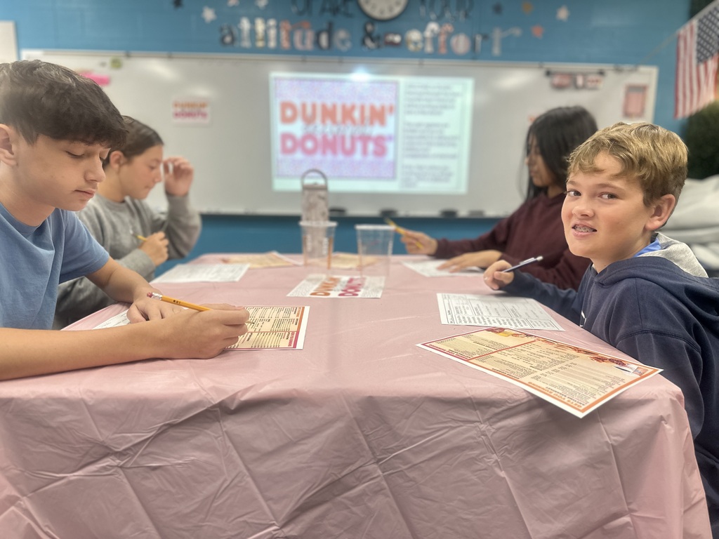 Boys are sitting at their table looking at their menus, one is smiling at the camera.