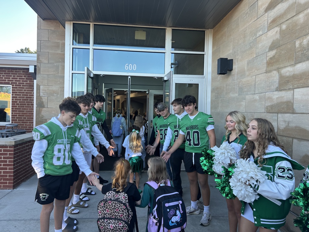 Football players greeting students