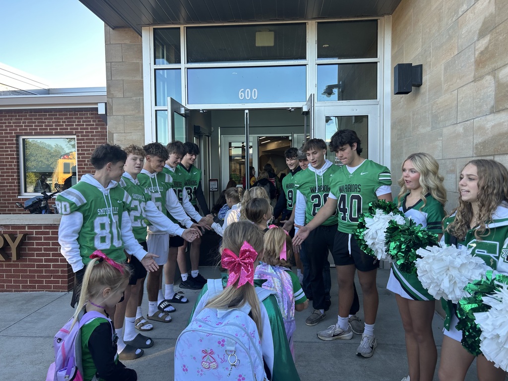Football players greeting students