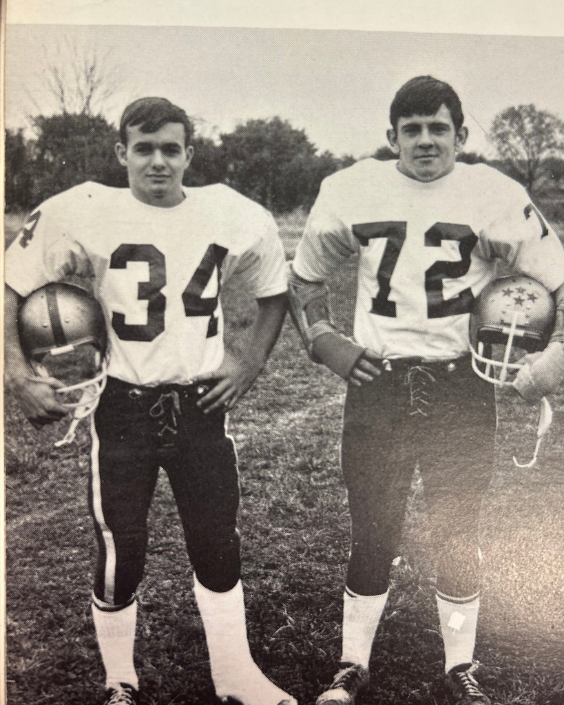 a black and white photo of football players from 1970 holding their helmets and one hand is on their hip with the jersey numbers 34 and 72.