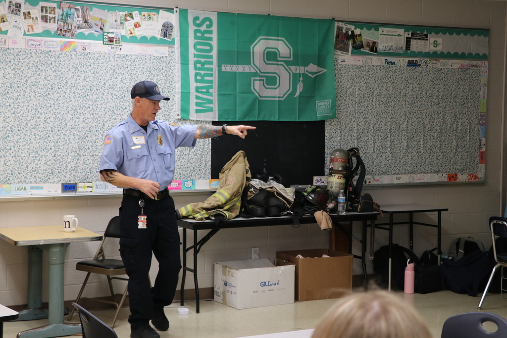 A fireman points to ask a student a question