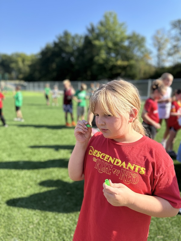 A girl blows bubbles while standing on the new turf area of the playground