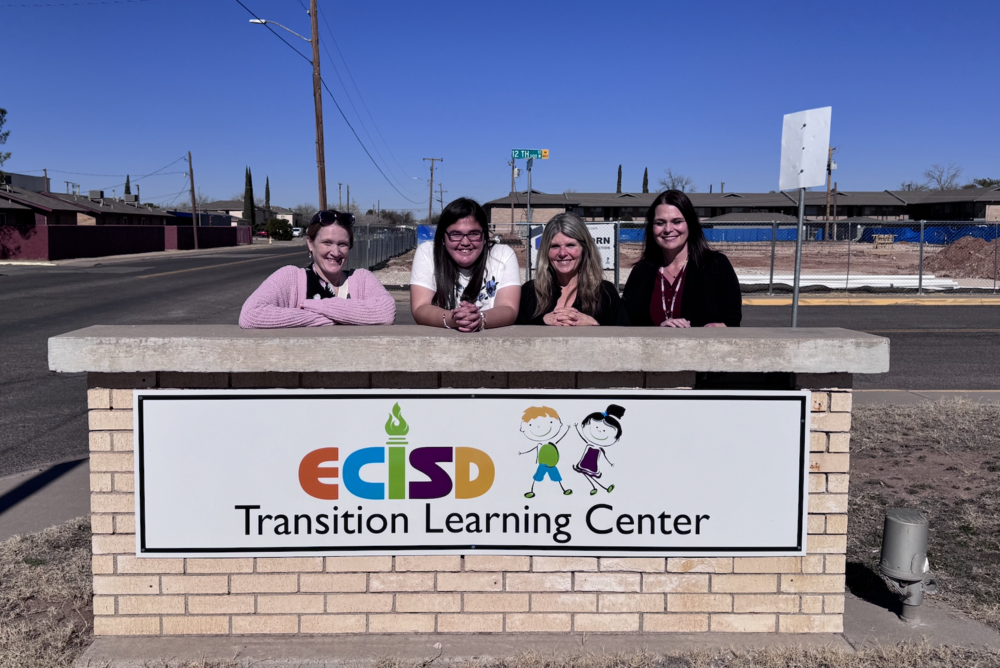 staff standing in front of sign 