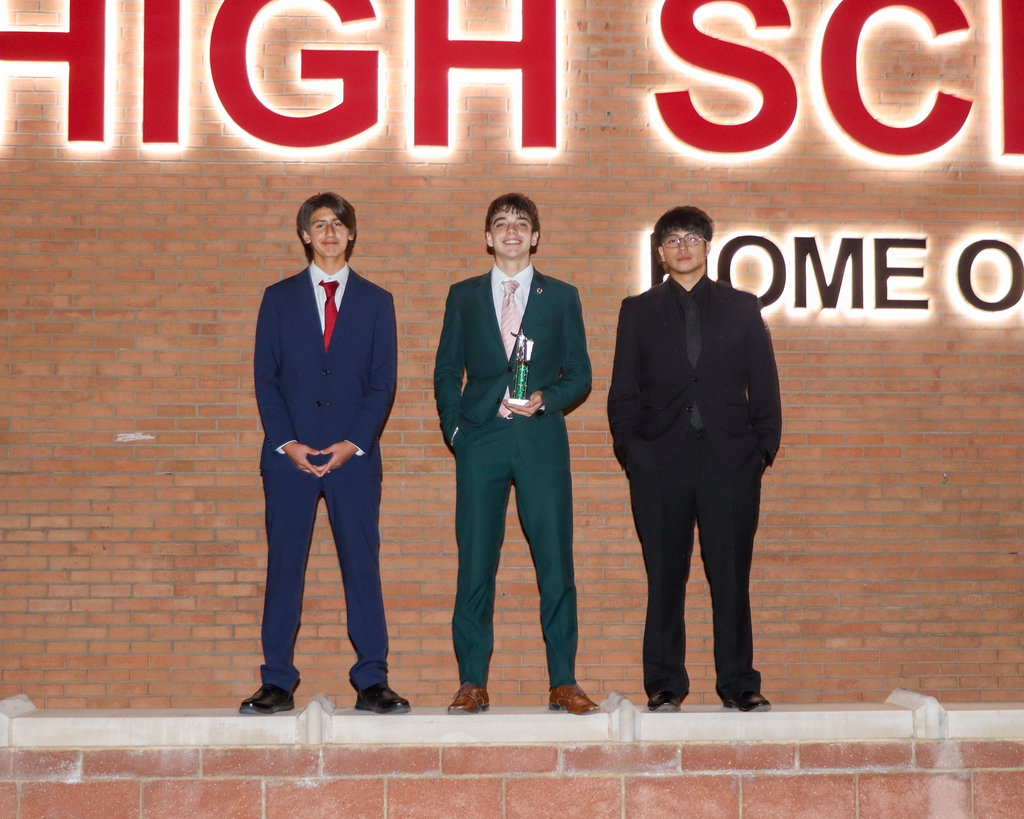 three students standing in front of high school