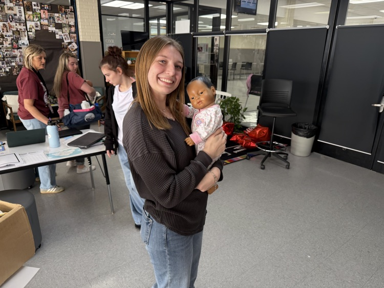 student posing with swaddled baby