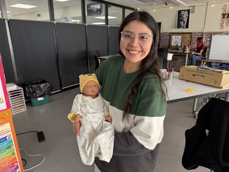 student posing with swaddled baby