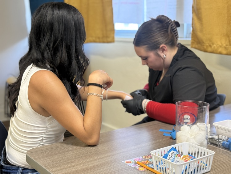 Photo of phlebotomy students practicing sticks on student volunteers