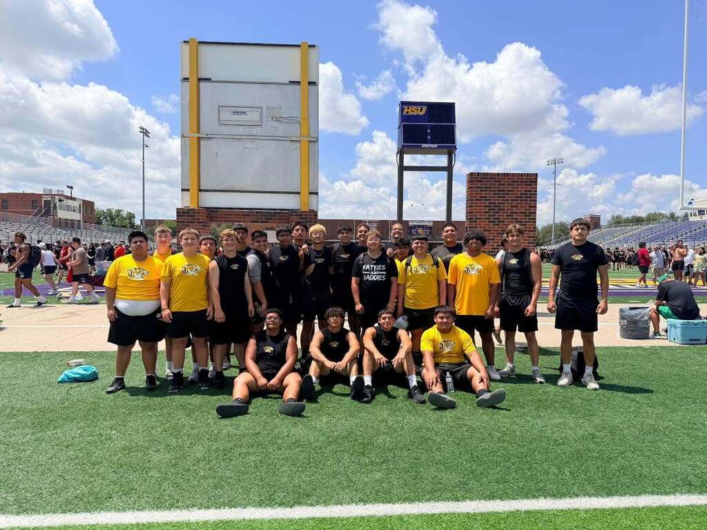 group of boys standning and sitting on green turf football field