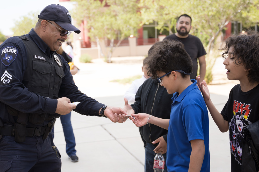 Police officer smiling and giving student a sticker