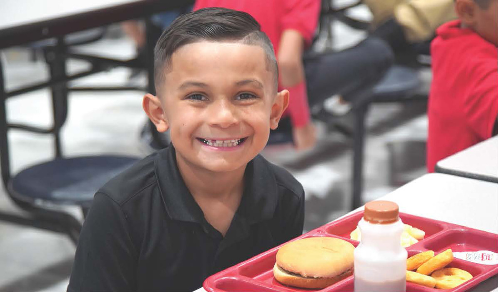 Elementary student eating school meal