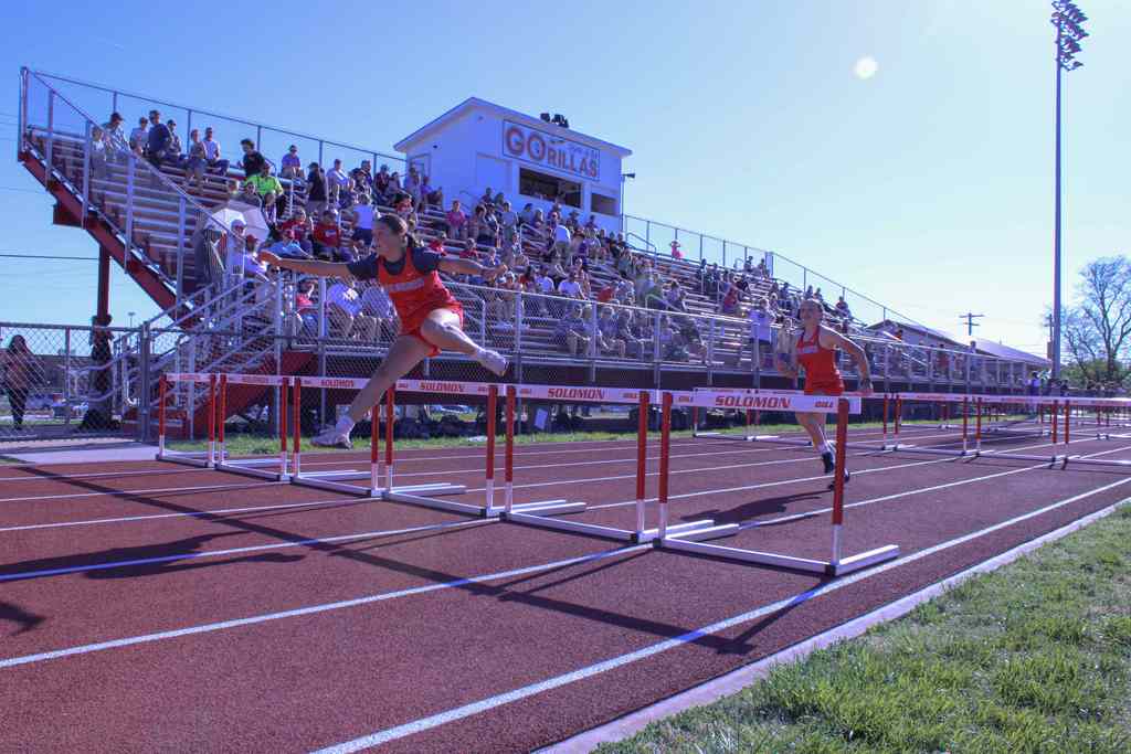 students jumping hurdles with Solomon stadiujm in background