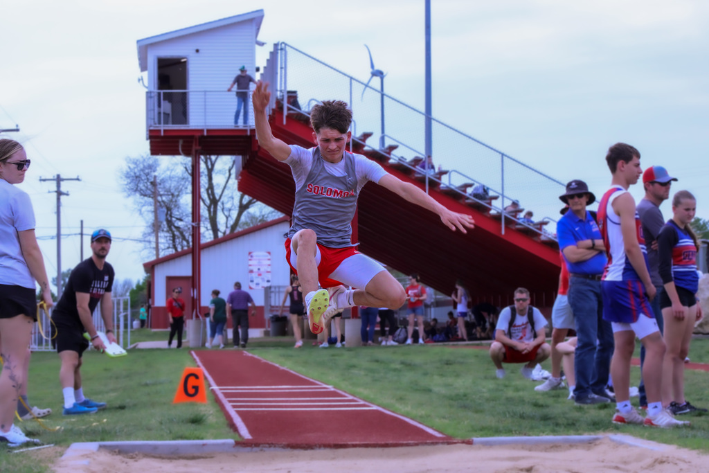 student mid air jumping for long jump