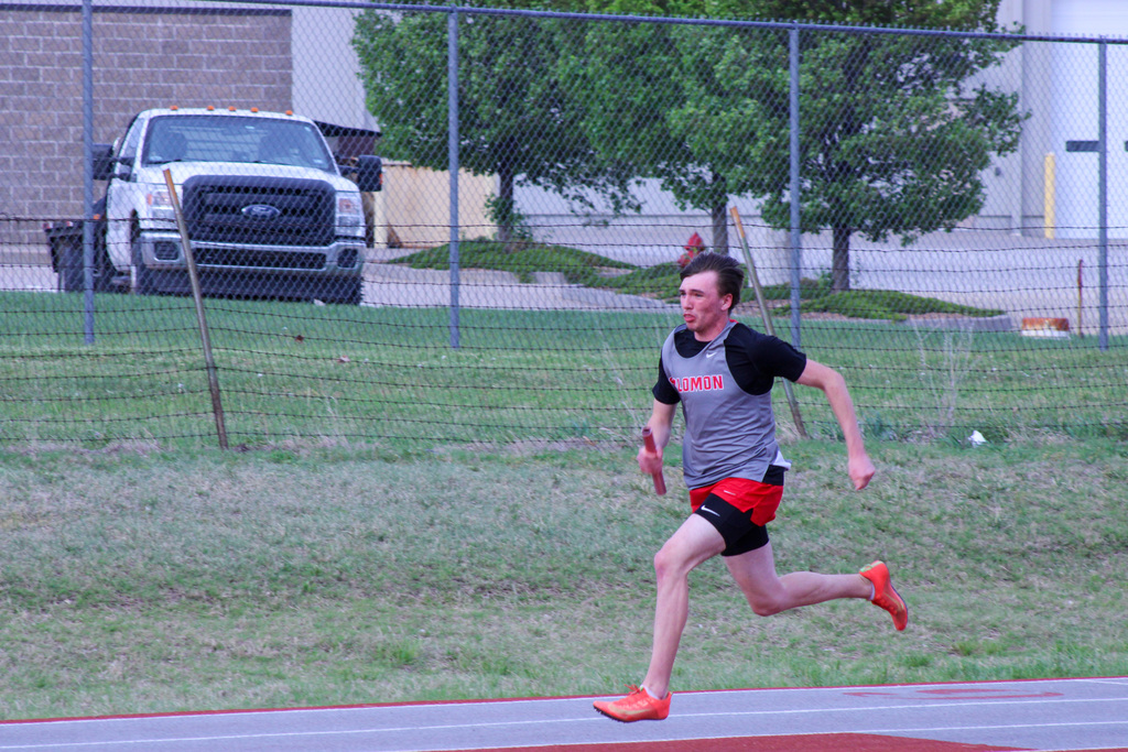 student mid race for a relay holding baton