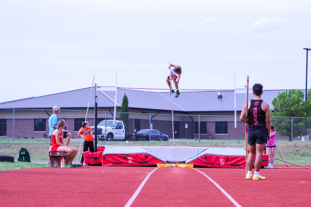 student mid air pole vaulting